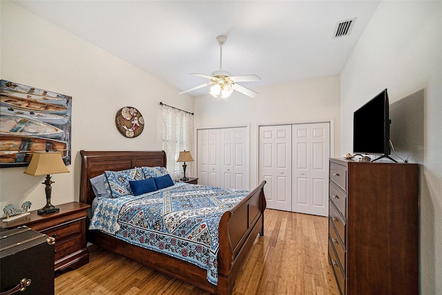 bedroom with multiple closets, ceiling fan, and light hardwood / wood-style floors