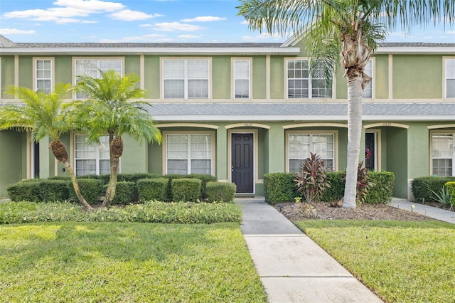 multi unit property with a front lawn and stucco siding