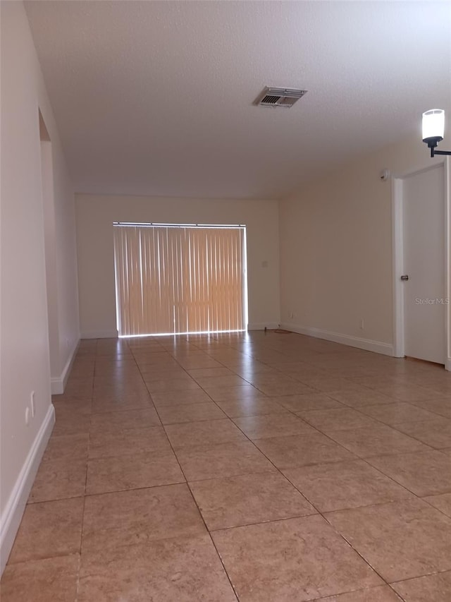 4606 W Gray St Unit 110, Tampa, FL 33609 - empty room featuring light tile patterned floors, baseboards, and a textured ceiling