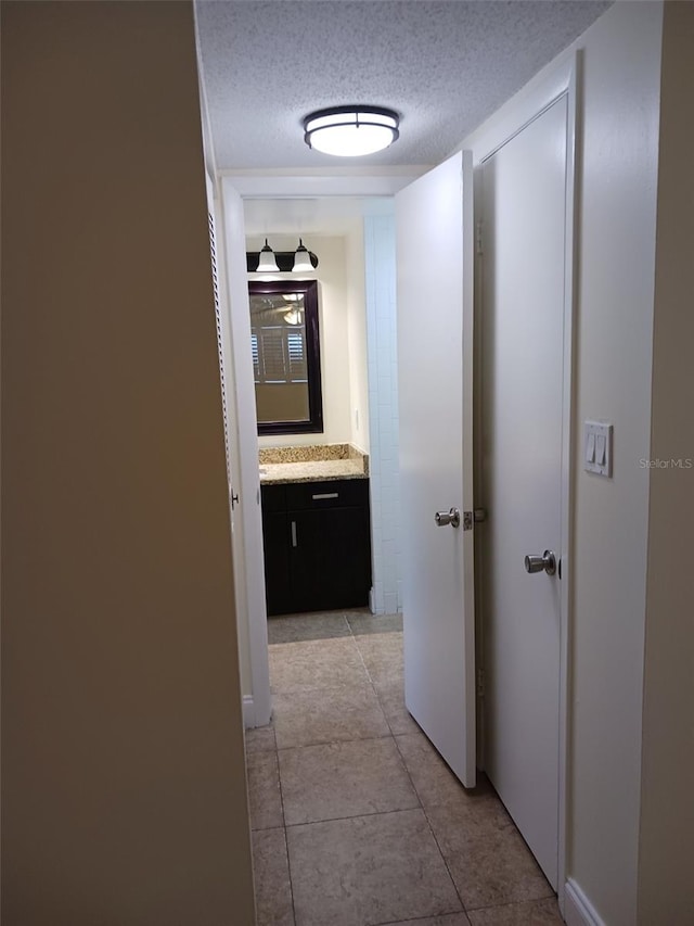 hall with light tile patterned flooring and a textured ceiling