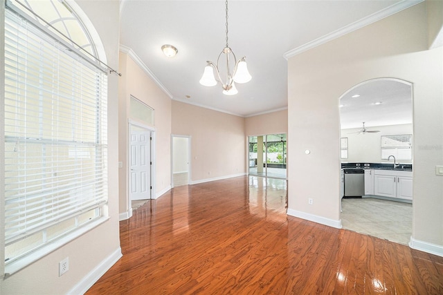 spare room with light wood-type flooring, ceiling fan with notable chandelier, sink, and ornamental molding