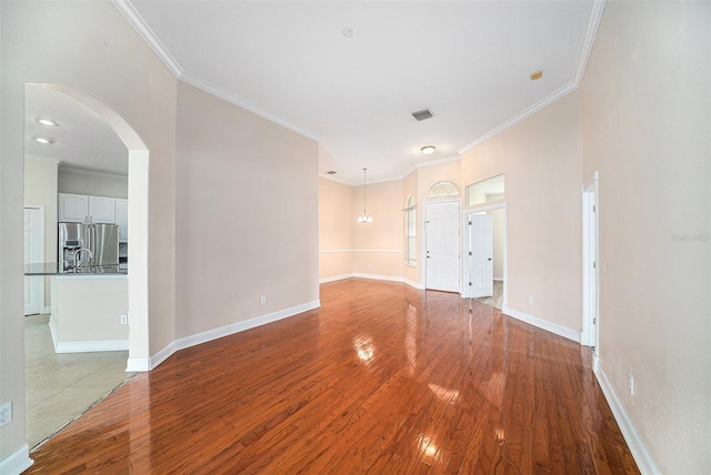 unfurnished room featuring ornamental molding, sink, and light hardwood / wood-style floors