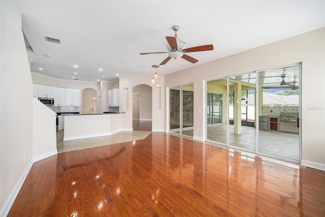 unfurnished living room with light wood-type flooring, ceiling fan, and sink