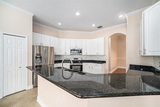 kitchen with dark stone counters, appliances with stainless steel finishes, and white cabinets