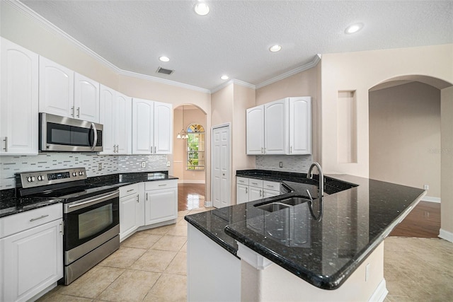 kitchen with backsplash, stainless steel appliances, dark stone counters, and sink