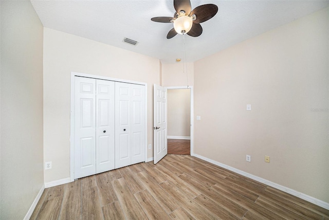 unfurnished bedroom with light wood-type flooring, ceiling fan, and a closet