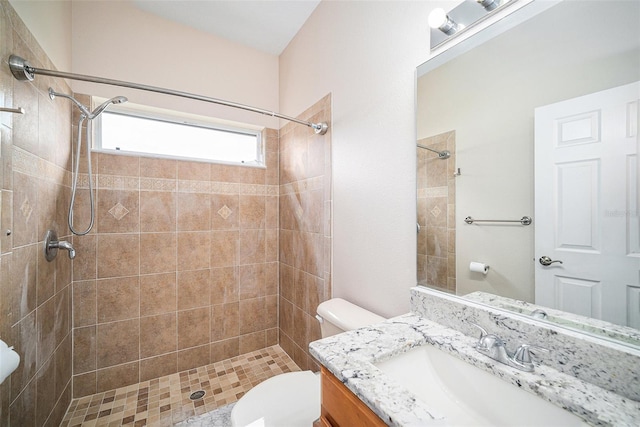 bathroom with tiled shower, vanity, and toilet