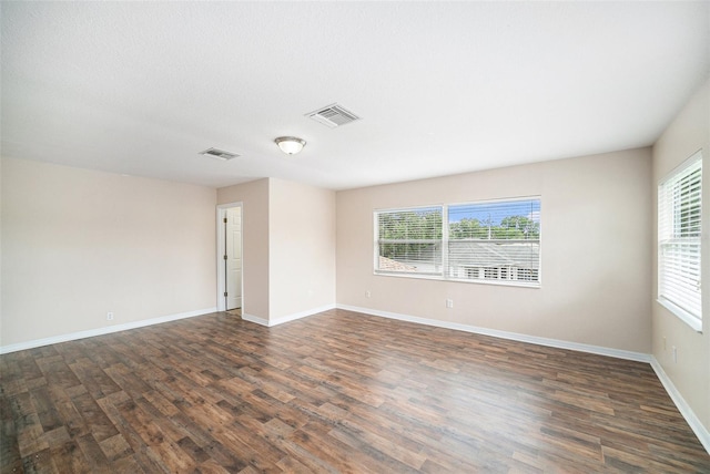 empty room featuring a wealth of natural light and dark hardwood / wood-style flooring