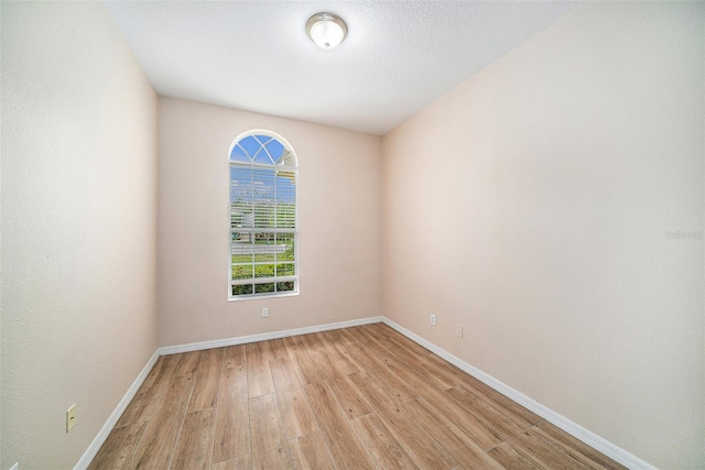 empty room with a textured ceiling and light hardwood / wood-style flooring