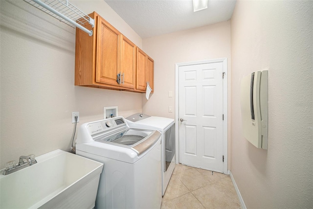 washroom with light tile patterned floors, sink, separate washer and dryer, cabinets, and a textured ceiling