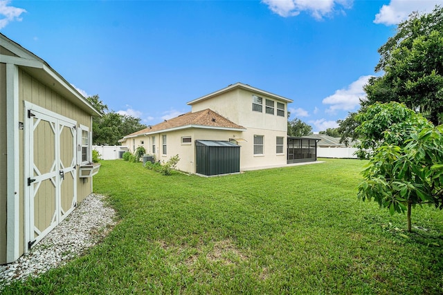 rear view of house with a yard, cooling unit, and a storage shed