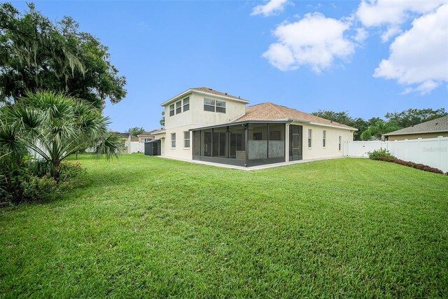 back of property with a sunroom and a yard