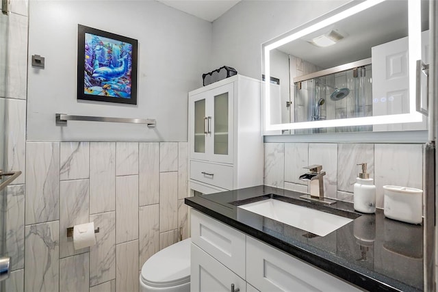 bathroom with tile walls, toilet, vanity, and walk in shower