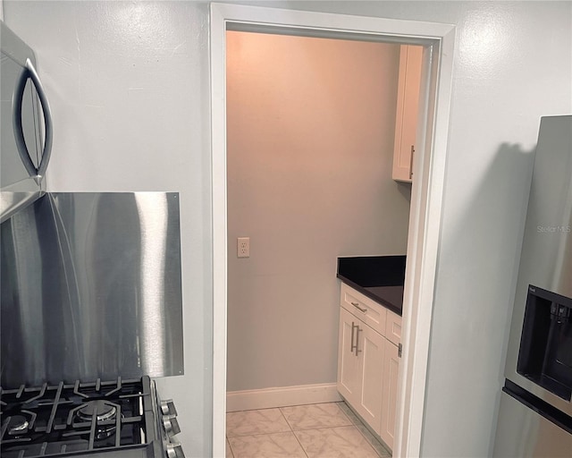 1819 Shore Dr S Unit 318, South Pasadena, FL 33707 - kitchen featuring stainless steel fridge, light marble finish flooring, white cabinetry, dark countertops, and baseboards