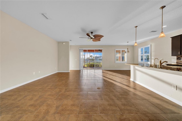 unfurnished living room with ceiling fan and dark tile patterned flooring