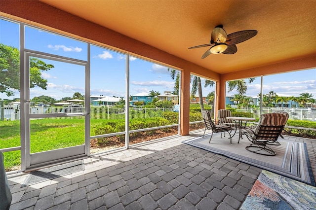 unfurnished sunroom with ceiling fan