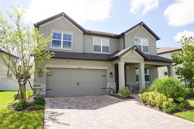 craftsman inspired home with stone siding, stucco siding, an attached garage, and decorative driveway