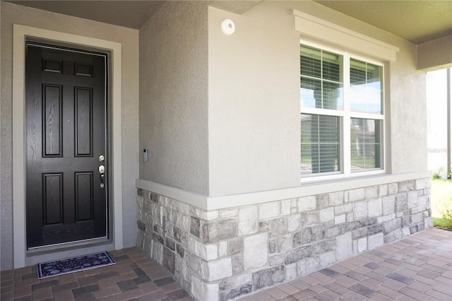 entrance to property featuring stucco siding and stone siding