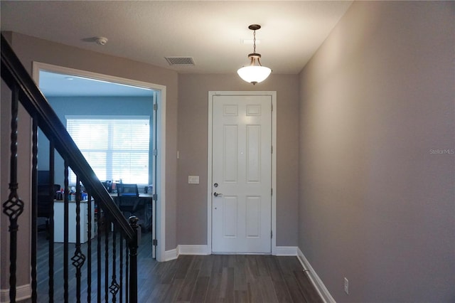 entrance foyer featuring visible vents, baseboards, dark wood-type flooring, and stairway