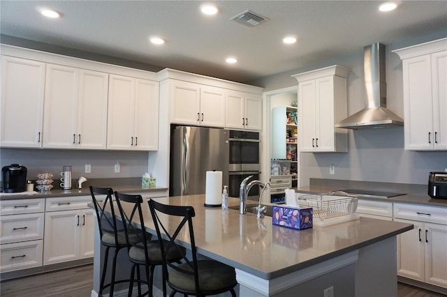 kitchen featuring white cabinets, wall chimney exhaust hood, visible vents, and stainless steel appliances