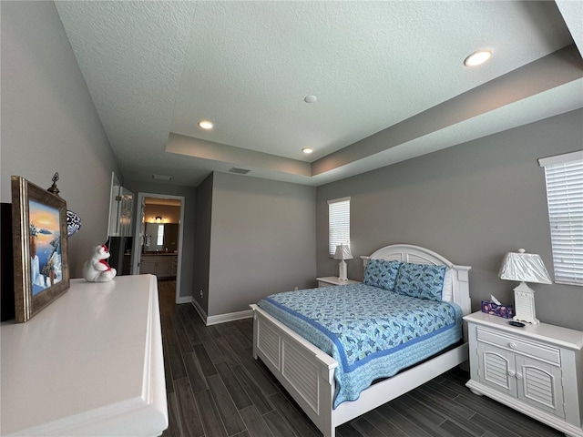 bedroom with visible vents, baseboards, a raised ceiling, and wood tiled floor