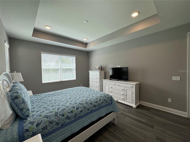 bedroom with a textured ceiling, a raised ceiling, baseboards, and wood tiled floor