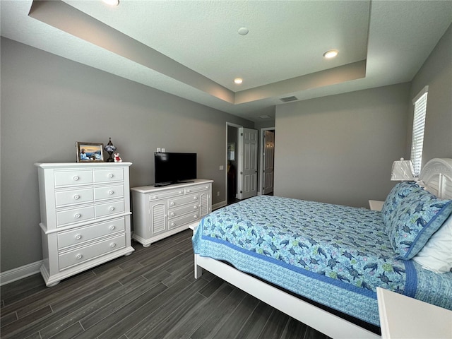 bedroom with recessed lighting, a tray ceiling, baseboards, and wood tiled floor