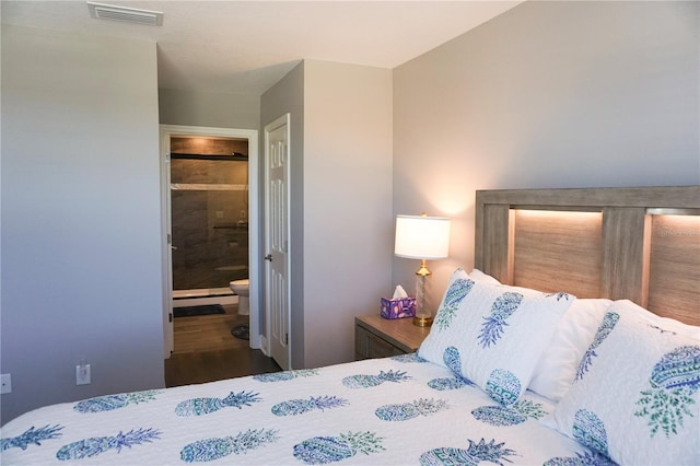 bedroom featuring visible vents, connected bathroom, and wood finished floors