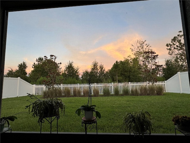 yard at dusk featuring a fenced backyard