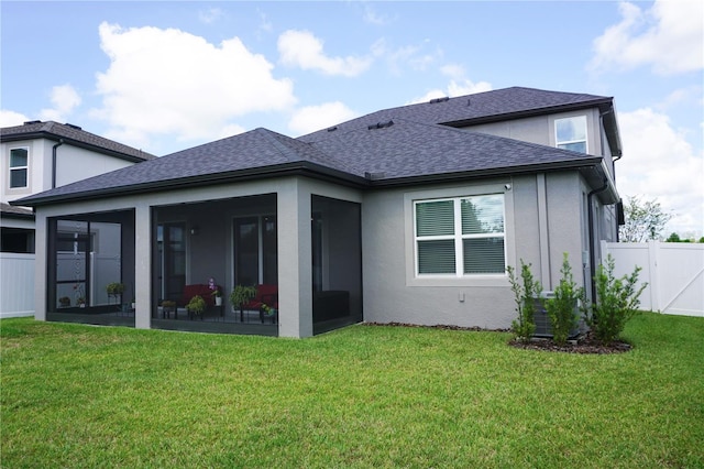 back of house with a shingled roof, fence, stucco siding, a yard, and a sunroom