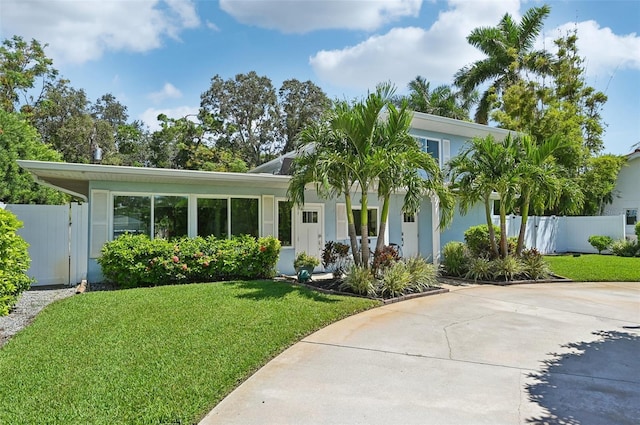 view of front of house with a front lawn, fence, a gate, and stucco siding