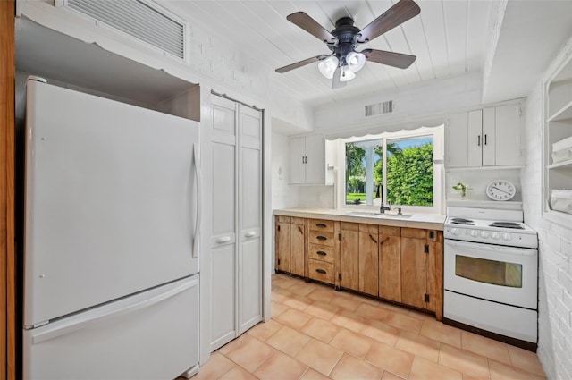 kitchen featuring light countertops, visible vents, a sink, brick wall, and white appliances