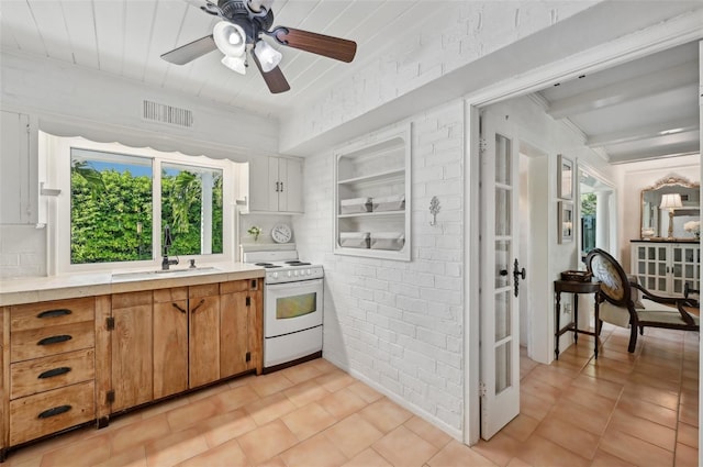 kitchen featuring white range with electric stovetop, visible vents, brick wall, light countertops, and a sink