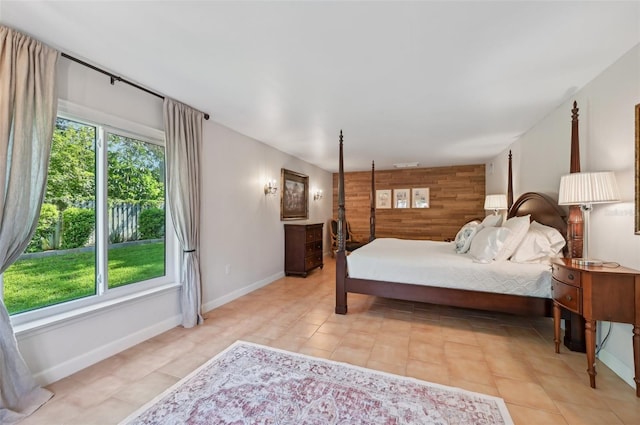 bedroom with baseboards, an accent wall, multiple windows, and wooden walls