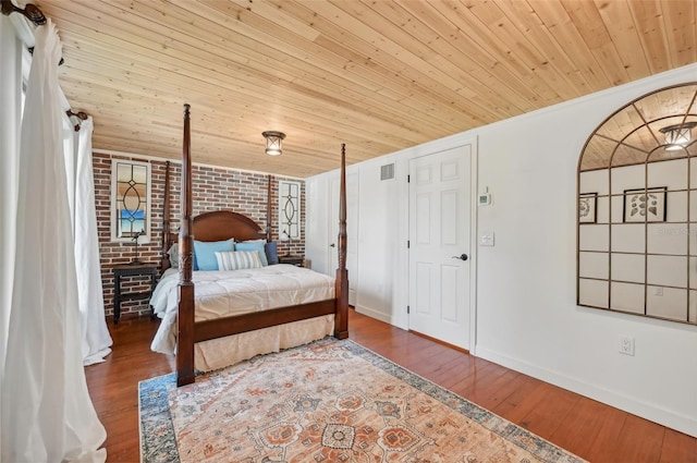 bedroom with wooden ceiling, brick wall, baseboards, and wood finished floors