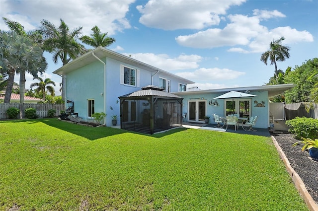 back of property featuring fence, a gazebo, french doors, a lawn, and stucco siding