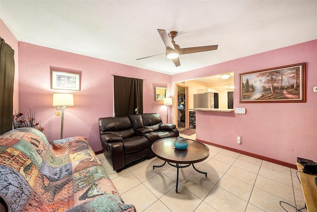 living room with a textured ceiling, ceiling fan, and light tile patterned floors