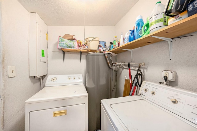 clothes washing area with a textured ceiling, electric panel, separate washer and dryer, and water heater