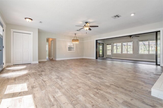 unfurnished living room featuring light wood-type flooring and ceiling fan with notable chandelier