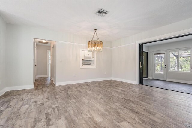 spare room featuring hardwood / wood-style floors and a notable chandelier