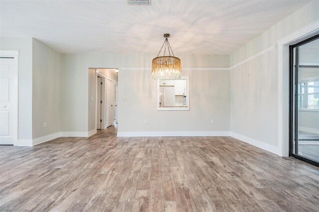 unfurnished dining area with light wood-type flooring and an inviting chandelier