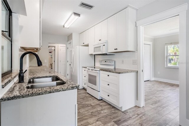 kitchen featuring dark stone countertops, sink, white appliances, and white cabinets