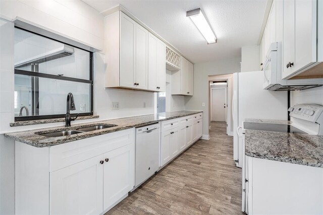 kitchen featuring white appliances, light hardwood / wood-style flooring, sink, stone countertops, and white cabinets