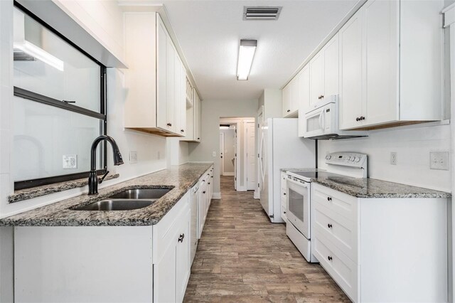 kitchen with sink, white appliances, hardwood / wood-style flooring, and white cabinets