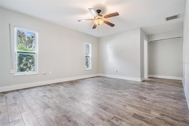 empty room featuring ceiling fan, a wealth of natural light, and light hardwood / wood-style floors