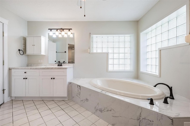 bathroom with tile patterned flooring, vanity, and tiled tub