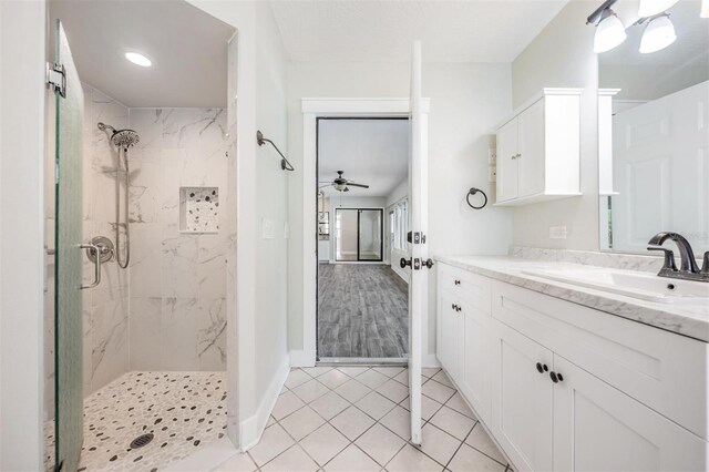 bathroom with tiled shower, vanity, ceiling fan, and tile patterned floors