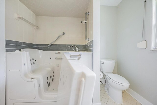 bathroom featuring tile patterned flooring, toilet, and a washtub