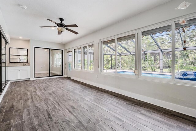 unfurnished sunroom featuring ceiling fan and a healthy amount of sunlight