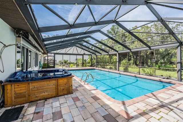 view of pool with a lanai, a hot tub, and a patio area